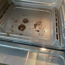 Open oven with visible burnt food stains and residue on the bottom interior surface.